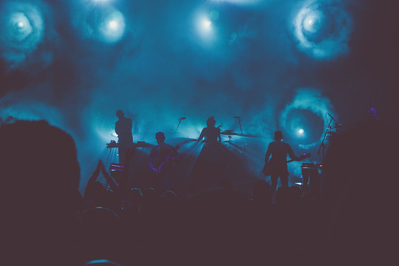 Silhouetted band performing on a smoke-filled stage with dramatic lighting.